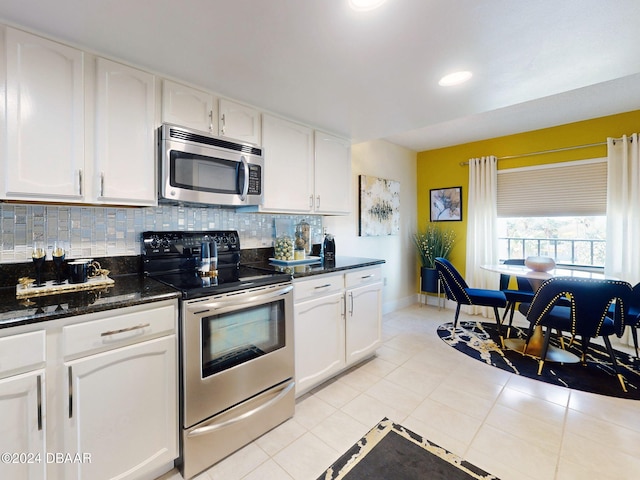 kitchen featuring appliances with stainless steel finishes, backsplash, dark stone counters, white cabinetry, and light tile patterned flooring