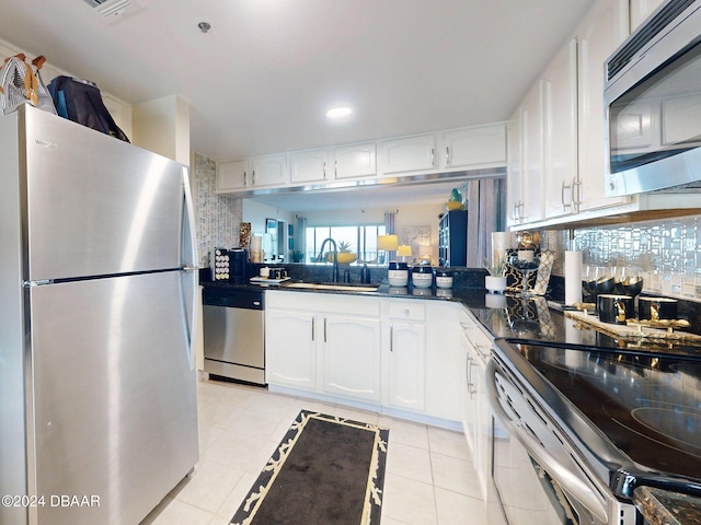 kitchen with appliances with stainless steel finishes, backsplash, white cabinetry, and light tile patterned floors