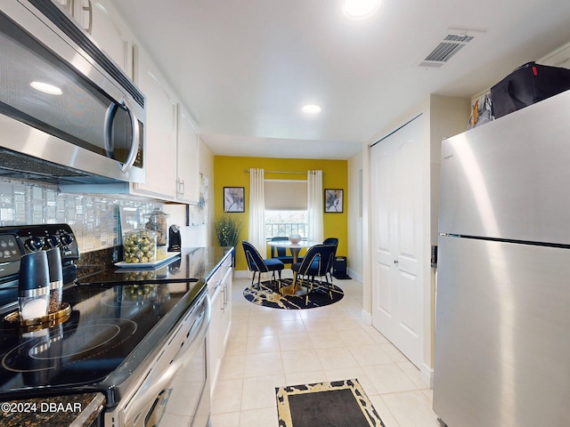 kitchen with white cabinets, light tile patterned floors, backsplash, and stainless steel appliances