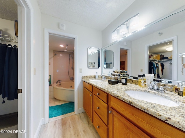 bathroom with hardwood / wood-style flooring, vanity, shower / tub combination, and a textured ceiling