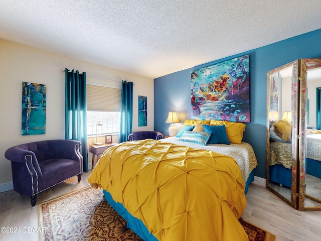 bedroom featuring a textured ceiling and light hardwood / wood-style flooring