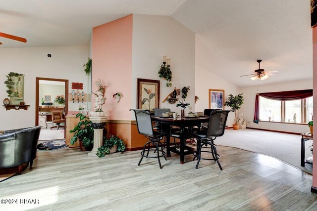 dining room featuring light hardwood / wood-style floors, lofted ceiling, ceiling fan, and wooden walls