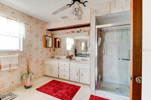 bathroom with vanity, a shower with door, a textured ceiling, and tile patterned floors