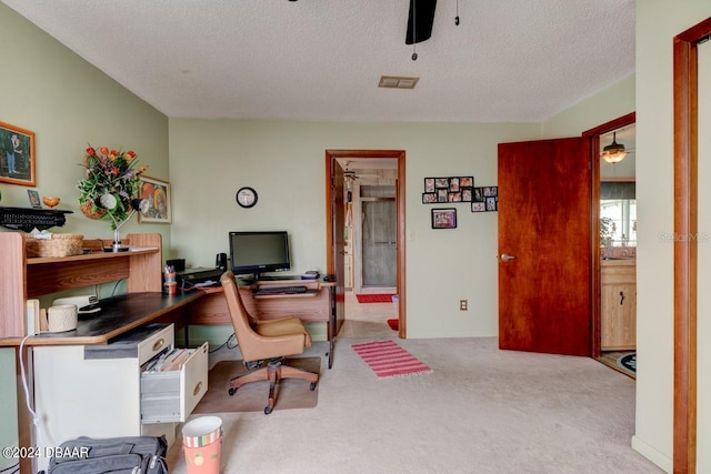 office featuring ceiling fan, a textured ceiling, and light carpet