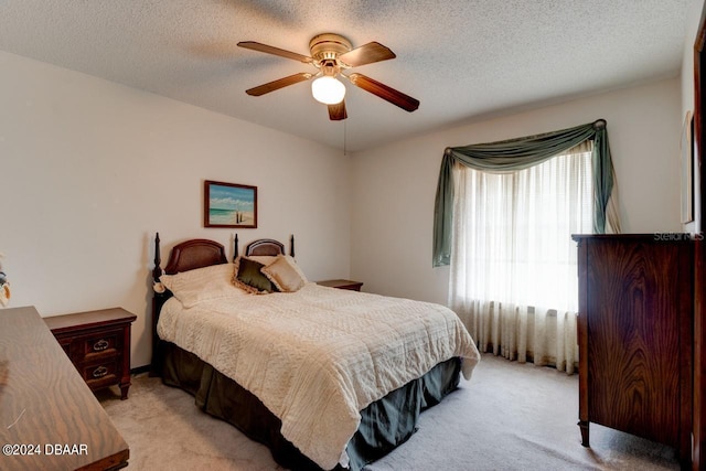 bedroom featuring a textured ceiling, light carpet, and ceiling fan