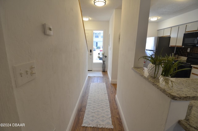 hallway with light hardwood / wood-style flooring and a textured ceiling