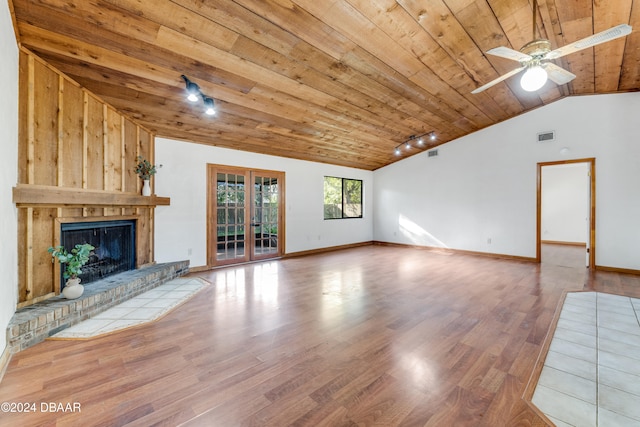 unfurnished living room featuring light hardwood / wood-style floors, ceiling fan, wood ceiling, a brick fireplace, and vaulted ceiling