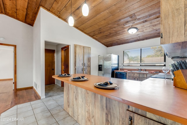 kitchen with vaulted ceiling, light tile patterned floors, wooden ceiling, decorative light fixtures, and stainless steel fridge