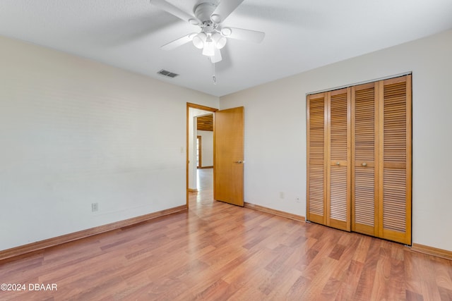 unfurnished bedroom featuring light hardwood / wood-style flooring, ceiling fan, and a closet