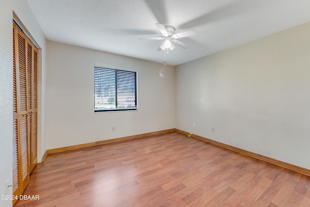 unfurnished bedroom featuring a textured ceiling, light hardwood / wood-style flooring, ceiling fan, and a closet