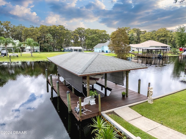 view of dock with a water view and a lawn