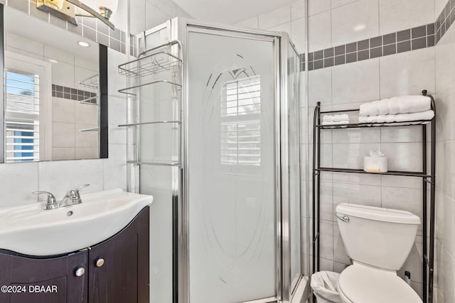 bathroom featuring vanity, toilet, an enclosed shower, and tile walls