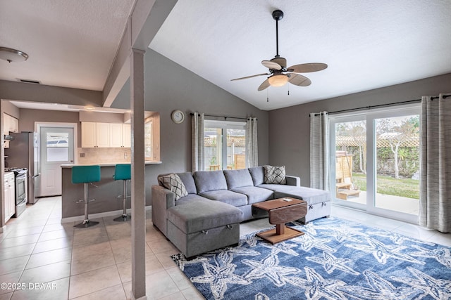 tiled living room with a textured ceiling, ceiling fan, and vaulted ceiling