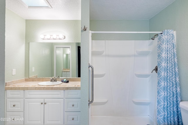 bathroom featuring toilet, a textured ceiling, a shower with shower curtain, and vanity