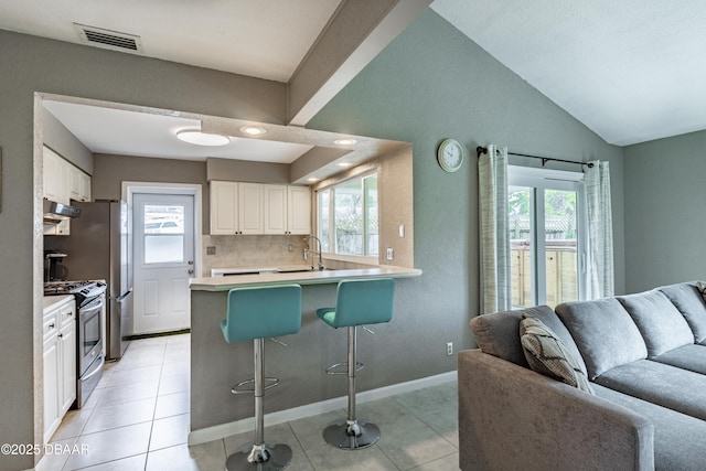 kitchen with a breakfast bar area, stainless steel range, kitchen peninsula, white cabinetry, and tasteful backsplash