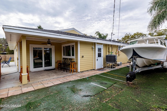 rear view of property featuring cooling unit, a patio, ceiling fan, and a lawn