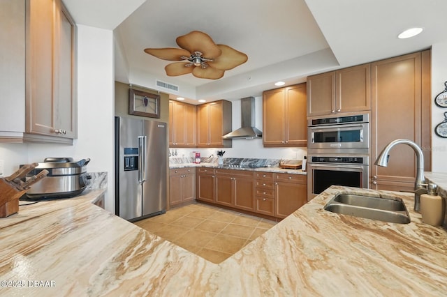 20 Porto Mar Unit 302, Palm Coast, FL 32137 - kitchen with stainless steel appliances, wall chimney exhaust hood, light tile patterned floors, brown cabinetry, and light stone countertops