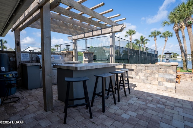 view of patio / terrace featuring an outdoor kitchen, a water view, an outdoor bar, and a pergola