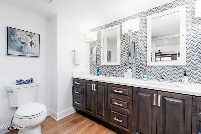 bathroom with tasteful backsplash, vanity, wood-type flooring, and toilet