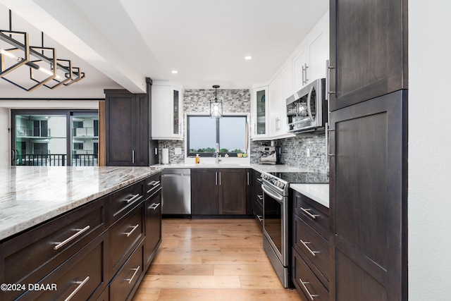 kitchen with white cabinets, decorative light fixtures, light hardwood / wood-style floors, and appliances with stainless steel finishes