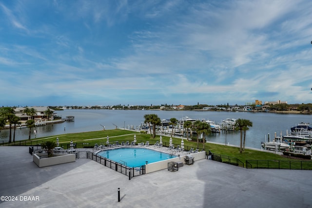 view of swimming pool with a yard, a water view, and a patio