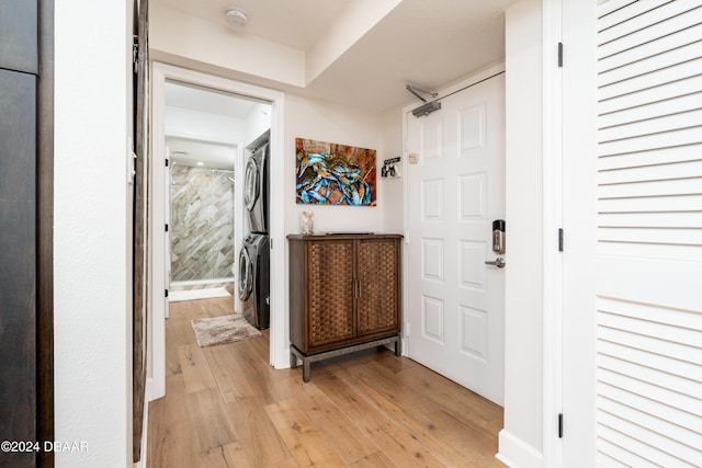 corridor with light hardwood / wood-style flooring and stacked washer / dryer