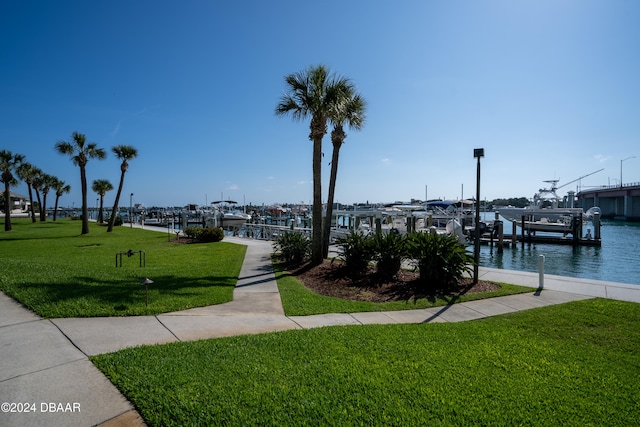 view of community featuring a boat dock, a water view, and a lawn