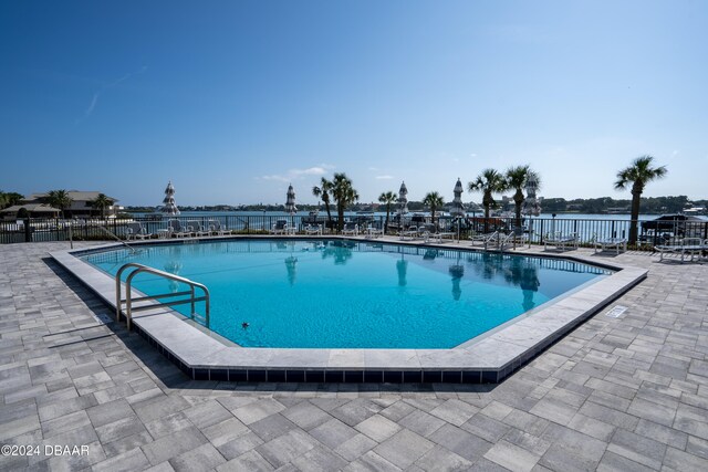 view of pool with a patio area and a water view