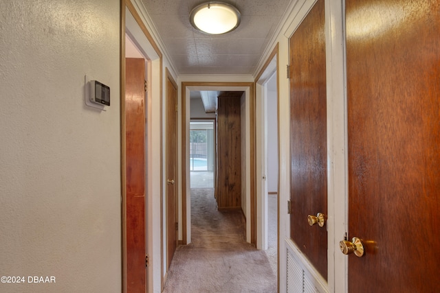 hallway with light colored carpet and crown molding