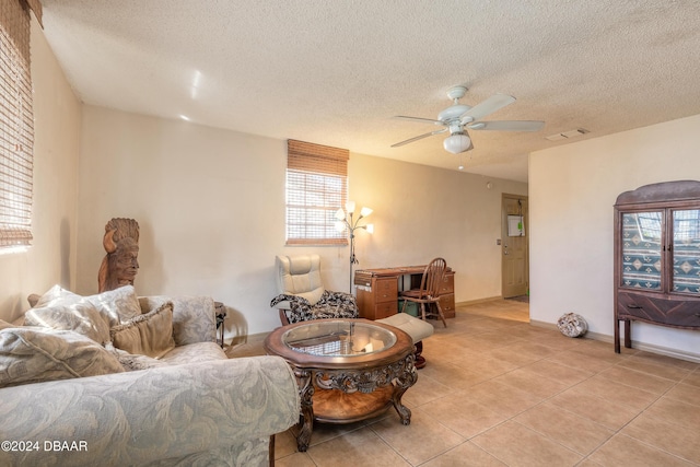 living room featuring ceiling fan, light tile patterned floors, and a textured ceiling