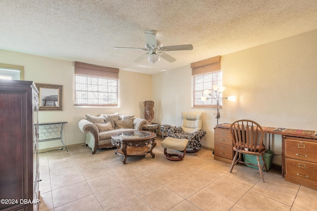 living area with ceiling fan, a healthy amount of sunlight, light tile patterned floors, and a textured ceiling