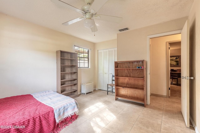 tiled bedroom with a textured ceiling, a closet, and ceiling fan