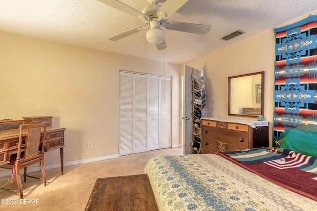 bedroom with ceiling fan, light tile patterned flooring, a textured ceiling, and a closet