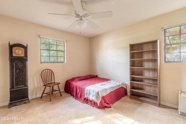 tiled bedroom with ceiling fan, a textured ceiling, and radiator