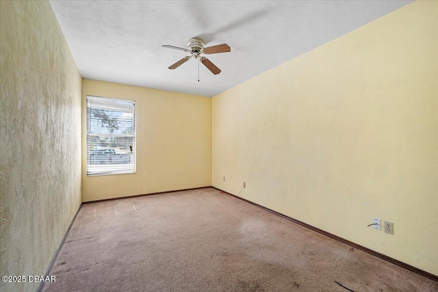 spare room featuring light carpet, ceiling fan, and baseboards