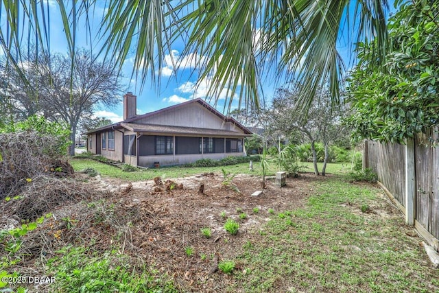 back of property with a sunroom, fence, and a chimney