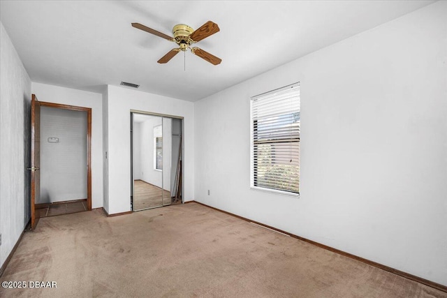 unfurnished bedroom featuring light carpet, a closet, visible vents, and a ceiling fan