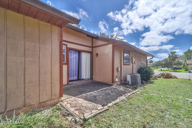 view of side of property featuring board and batten siding, a yard, and central air condition unit