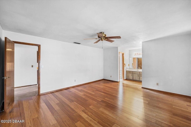 interior space with a ceiling fan, light wood-type flooring, visible vents, and baseboards