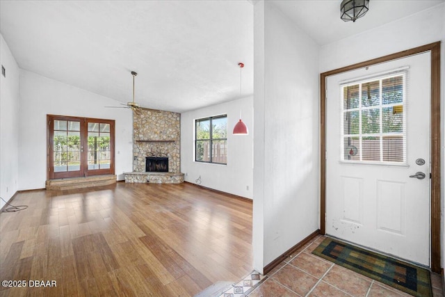 interior space with lofted ceiling, a stone fireplace, a wealth of natural light, and a ceiling fan