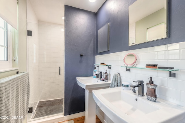 bathroom featuring decorative backsplash, double sink, and a shower with shower door