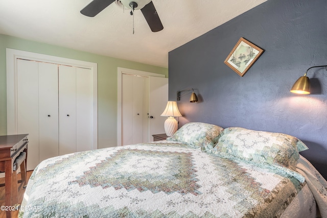 bedroom featuring hardwood / wood-style flooring, ceiling fan, and two closets