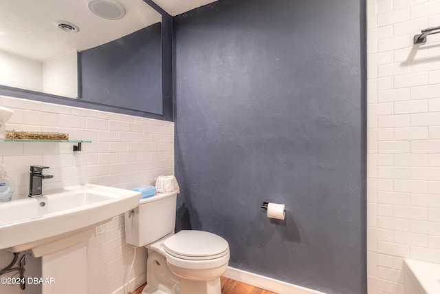 bathroom featuring tile walls, wood-type flooring, tasteful backsplash, and toilet