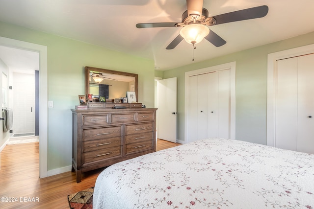 bedroom featuring light hardwood / wood-style floors, ceiling fan, and two closets