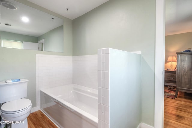 bathroom with a bathing tub, hardwood / wood-style flooring, and toilet