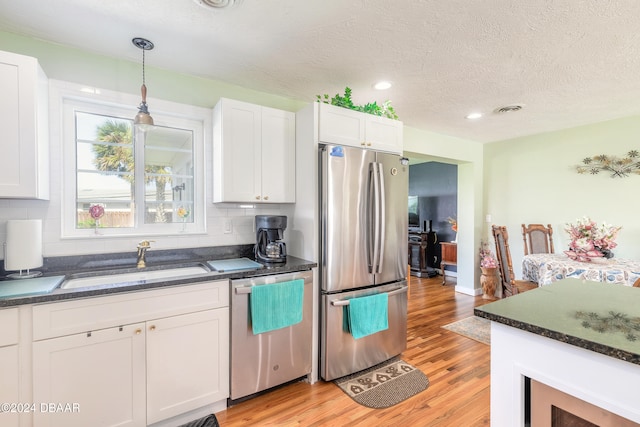 kitchen with stainless steel appliances, white cabinetry, tasteful backsplash, hanging light fixtures, and light hardwood / wood-style flooring