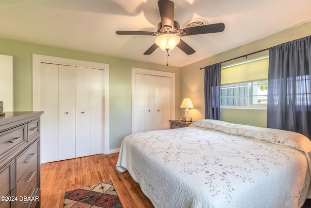 bedroom with ceiling fan, dark hardwood / wood-style floors, and multiple closets