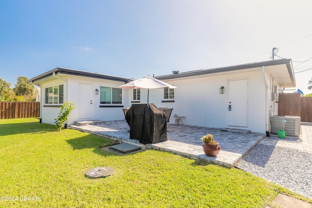 rear view of property with a lawn, central AC unit, and a patio area