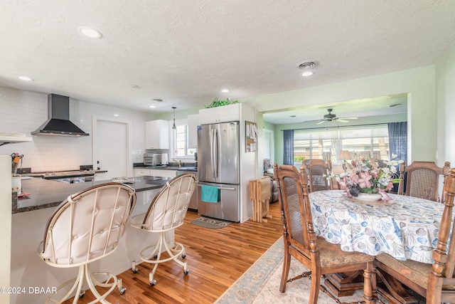 dining room with light wood-type flooring, a textured ceiling, and ceiling fan