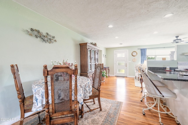 dining space with light hardwood / wood-style floors, ceiling fan, and a textured ceiling